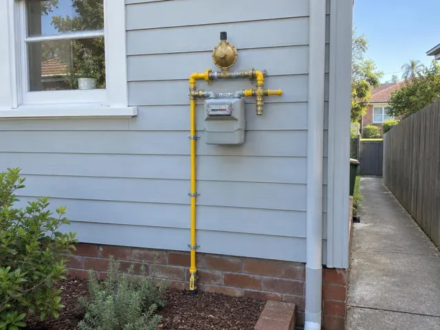 Exterior gas meter and new yellow gas piping on a weatherboard house wall in Freshwater
